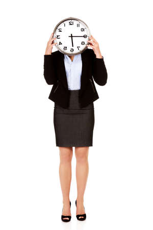Business woman covering face with a clock.の写真素材