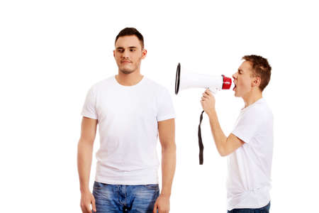 Young man shouting into a megaphone another man is trying not to hear.の写真素材
