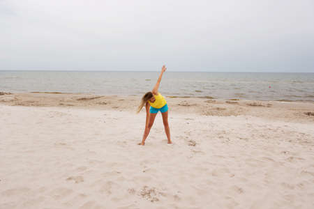 Young woman making yoga exercises on the beach.の写真素材