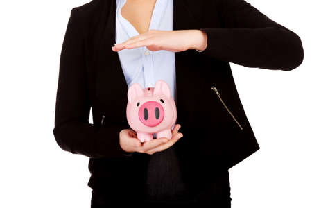 Young business woman protects piggybank.の写真素材