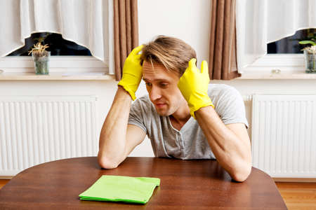 Tired man in yellow gloves sitting behind the desk.の写真素材