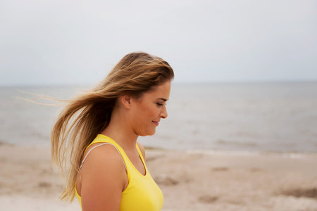 Tired woman standing on the beach.の写真素材