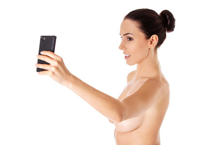 Nude beautiful woman taking selfie on white background. Isolated on white.