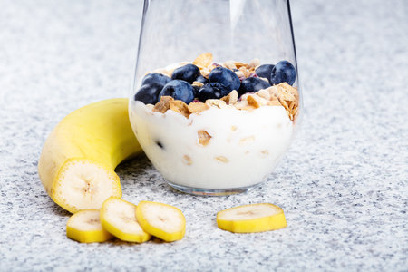 Dietetic breakfast - yoghurt with mueasli and huckleberries and bananaの写真素材