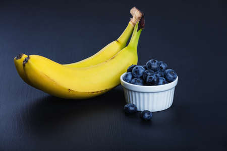 Two bananas and heap of huckleberriesの写真素材