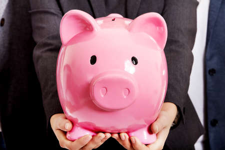 Business team-two men and woman holding piggybankの写真素材