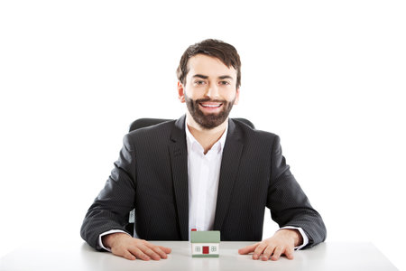 Businessman with a mini house in the office.の写真素材