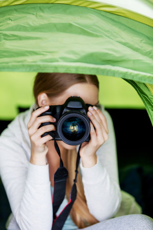 Young woman witho photo camera in a tent on the natureの写真素材