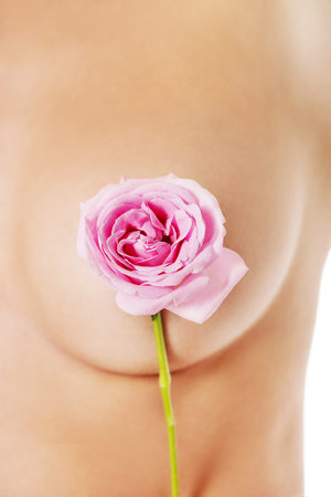 Beautiful woman covers breast with pink roseの写真素材
