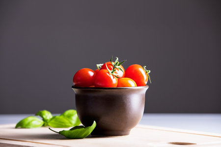 Ripe tomatoes in bowl and basilの写真素材