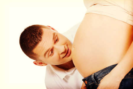 Happy father talking to mother's pregnant tummyの写真素材