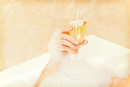Senior woman relaxing in bath with glass of champagne.の写真素材