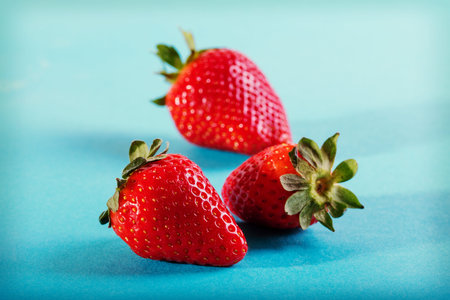 Three juicy strawberry on blue background.の写真素材