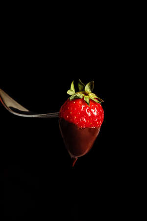 Silver fork with strawberry with chocolate.の写真素材