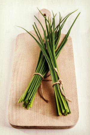 Fresh green chives on cutting board.