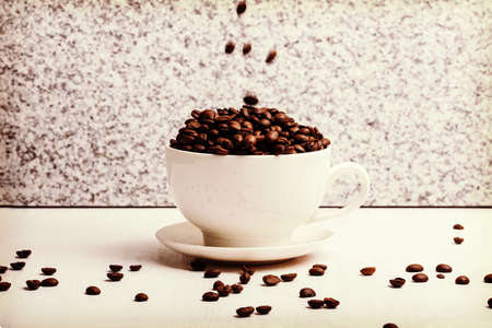 White cup with coffee seeds on granite background.の写真素材