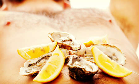 Oysters on mans belly.の写真素材