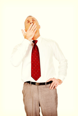 Exhausted and sleepy mature businessman yawning.の写真素材