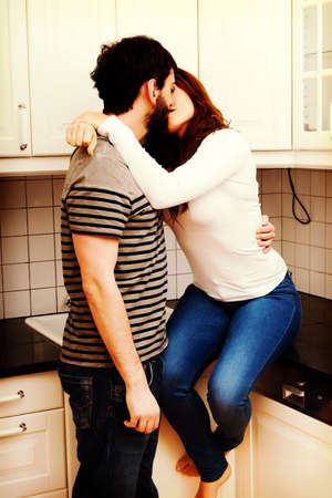Young beautiful couple kissing in the kitchen.の写真素材