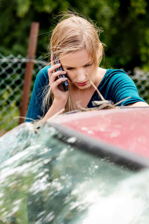 Woman dialing her phone after car crashの写真素材