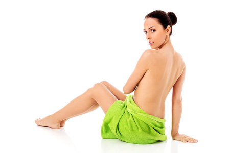 Woman wearing towel sitting on the floor, back view.の写真素材