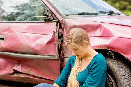 Upset driver woman in front of automobile crash car.の写真素材