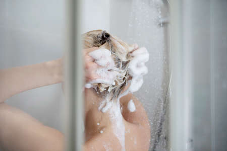 Beautiful naked woman washing her hair while taking shower.の写真素材