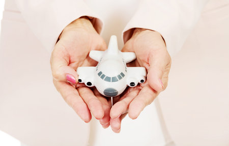 Elderly woman holding a toy plane on open plamsの写真素材