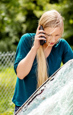 Woman dialing her phone after car crashの写真素材
