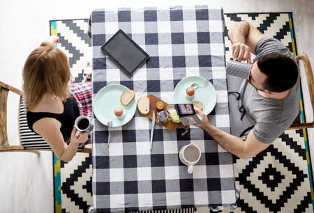 Loving couple sitting at a kitchen table, having a breakfast togetherの写真素材