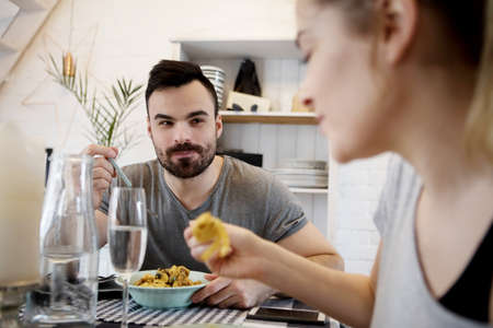Young couple sitting at the table and eating dinnerの写真素材