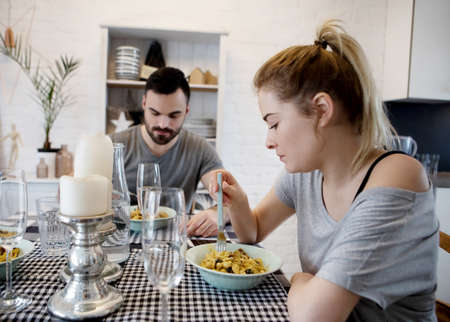 Young couple sitting at the table and eating dinnerの写真素材