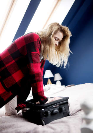 Woman struggling to close suitcaseの写真素材