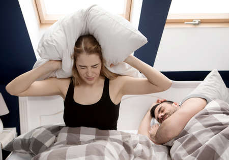 Snoring man in bed with wifeの写真素材