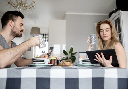 Loving couple sitting at a kitchen table, having a breakfast togetherの写真素材