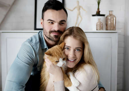 Happy couple with cat at homeの写真素材