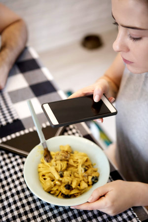 Woman taking photo of spaghetti with smart phoneの写真素材