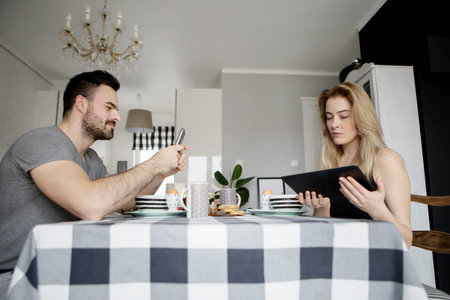 Loving couple sitting at a kitchen table, having a breakfast togetherの写真素材