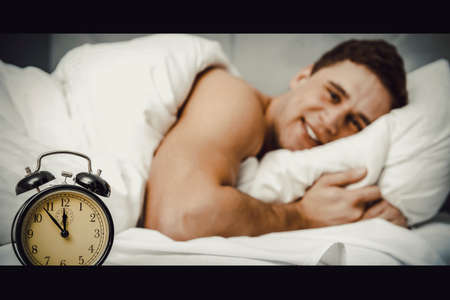 Man with alarm clock in bedroom.の写真素材