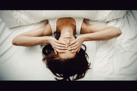 Sleepy woman waking up and rubbing her eyes.の写真素材
