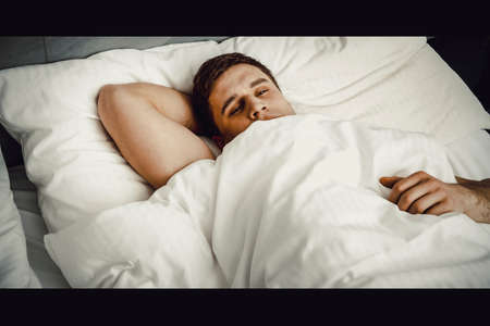 Handsome young man lying in bed.の写真素材