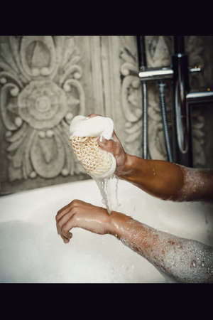 Beautiful bathing woman cleaning herself with sponge.の写真素材