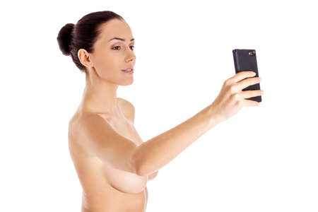 Nude beautiful woman taking selfie on white background.の写真素材