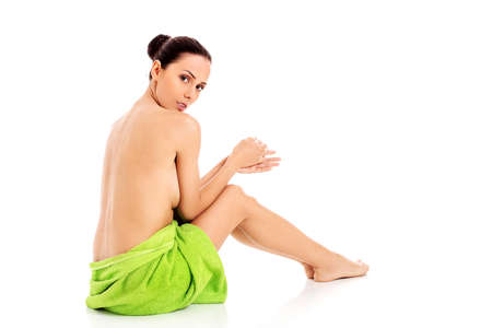 Woman wearing towel sitting on the floor, back view.の写真素材