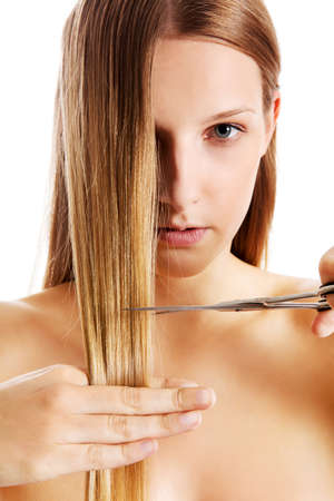 Young blonde woman cutting her hair with scissors.の写真素材