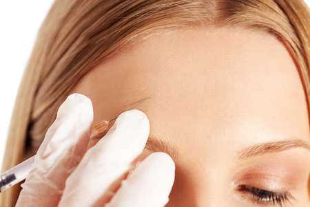 Closeup portrait of young woman getting cosmetic injection with syringe.の写真素材