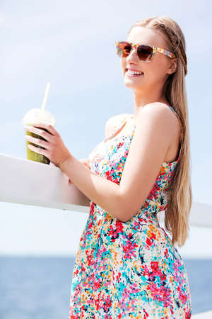 Beautiful young woman with sunglasses drinking green vegetable smoothie.の写真素材