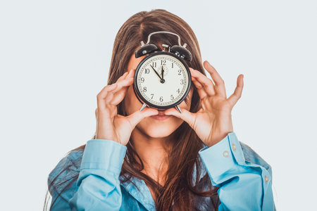 Morning woman in big shirt holding clock.の写真素材