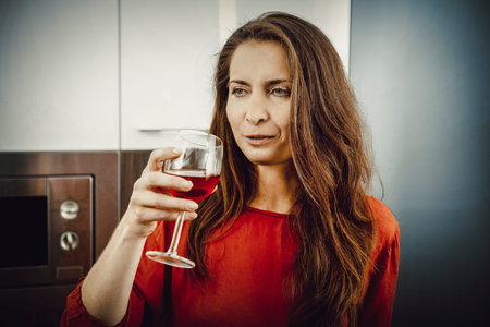 Woman with his wineglass in the kitchen.の写真素材
