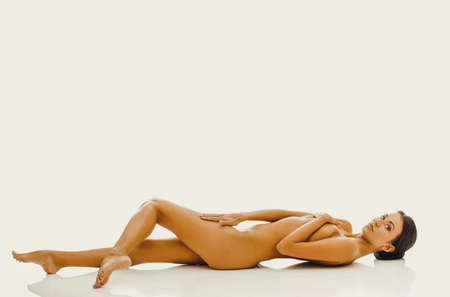 Nude woman on the floor covering intimate placesの写真素材